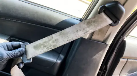 A car seat belt pulled out of its reel and held taut, showing grey-green mildew spotting along the damp webbing.
