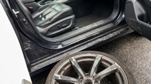 A lease car being checked before return, showing a worn shiny seat bolster, a scuffed door sill and a kerbed alloy wheel.