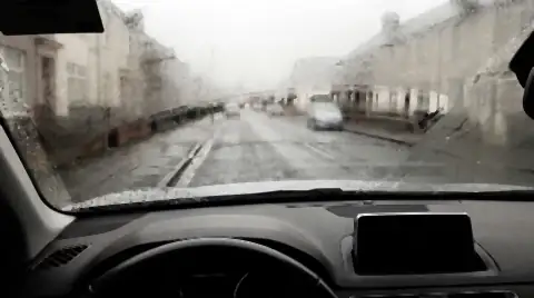 The inside of a car windscreen fogged with condensation, with one clear streak wiped through it and water beaded on the dashboard.